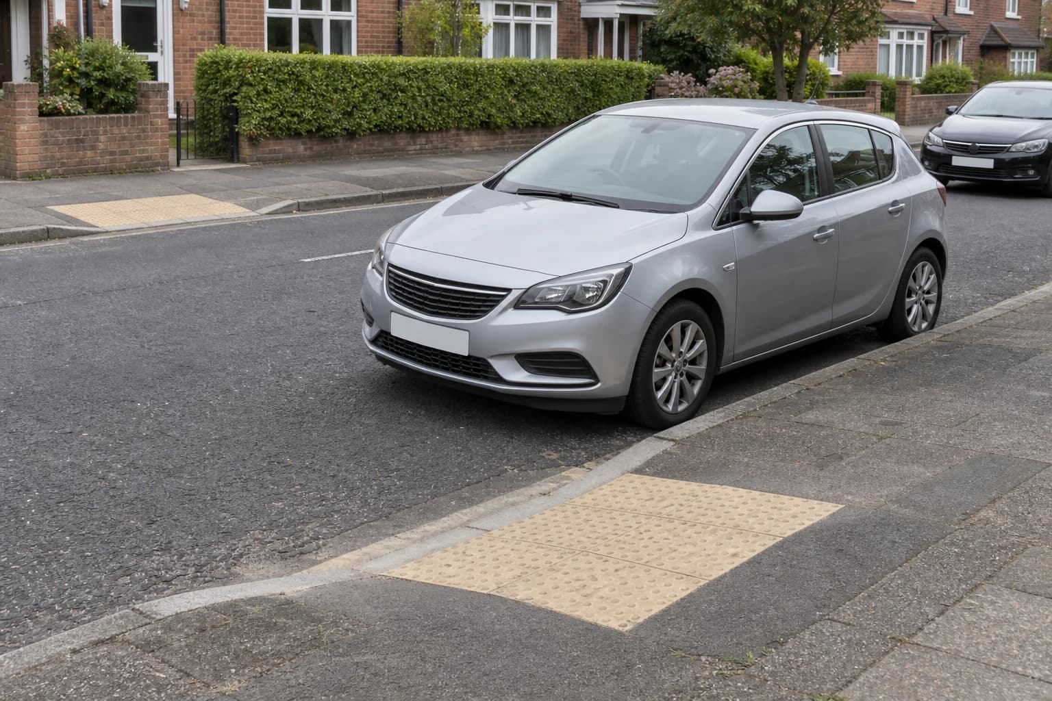 Car beside a pedestrian dropped kerb with tactile paving and a matching dropped kerb opposite.