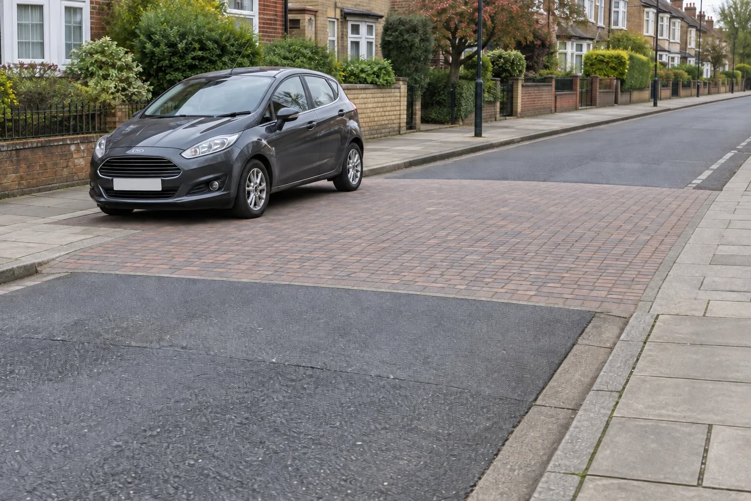 Car beside a raised pedestrian crossing where the carriageway is level with the pavement.