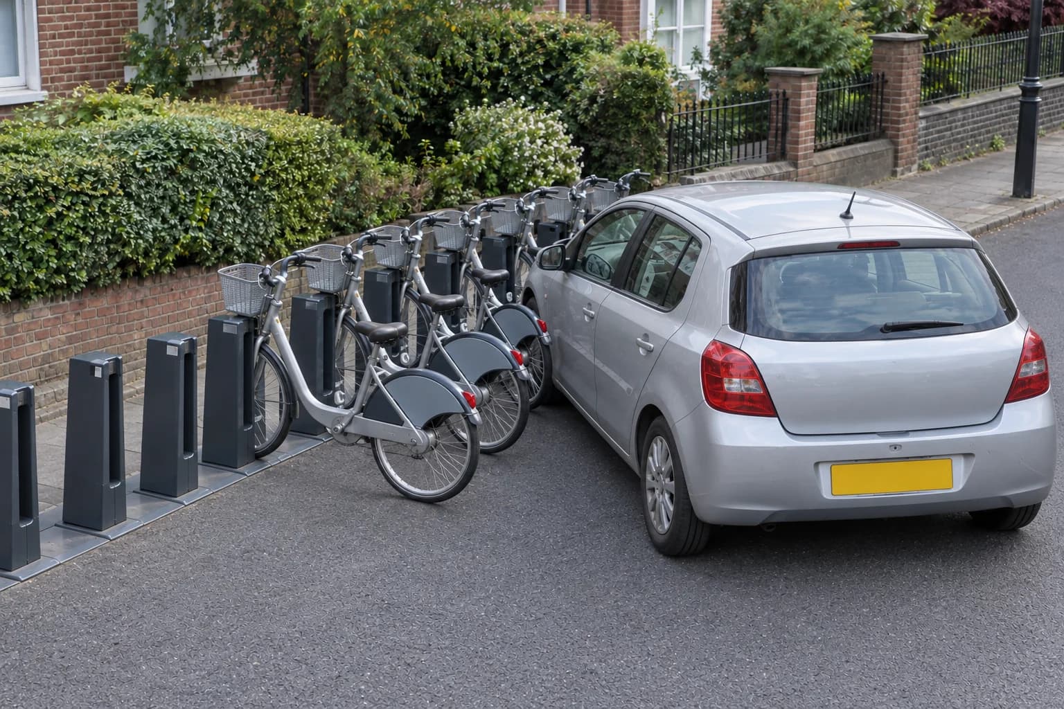 Car obstructing access beside an unbranded kerbside bicycle-hire docking station.