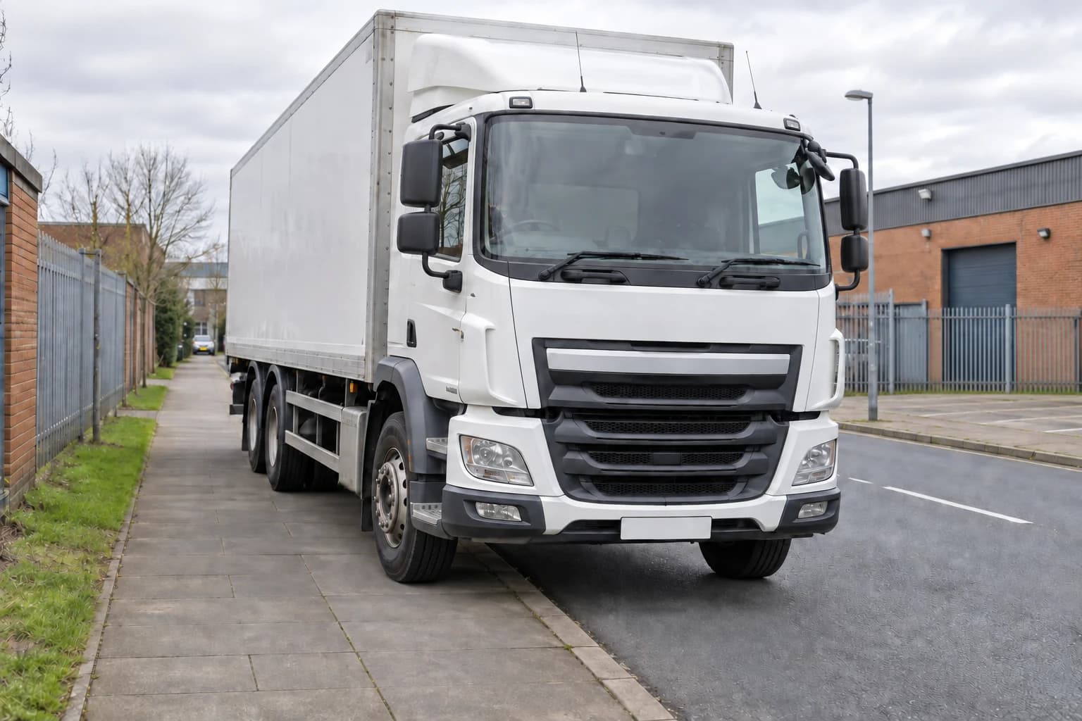 Heavy goods vehicle parked partly on a pavement beside a British road.