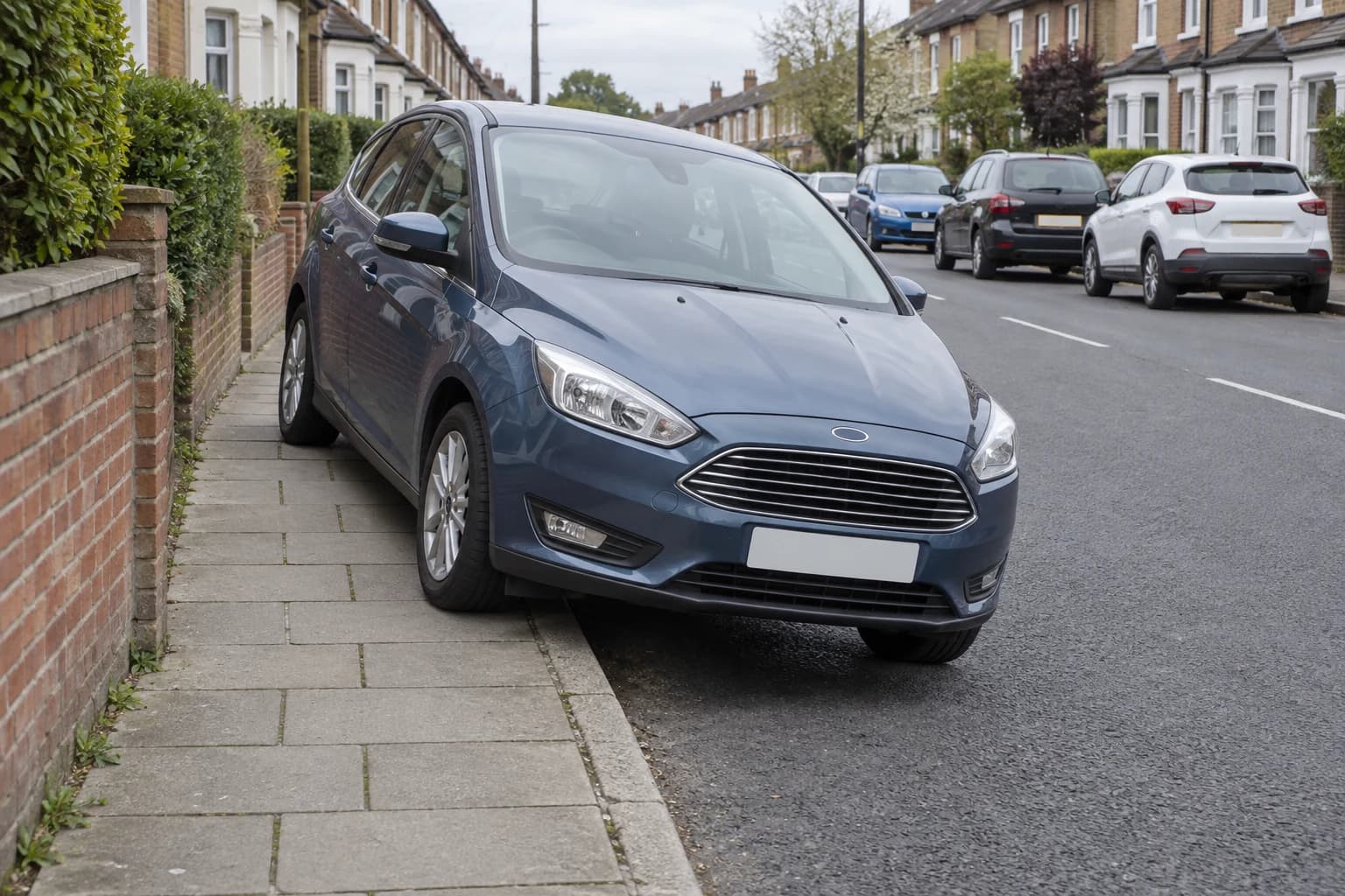 Car parked with two wheels on a pavement beside an ordinary British road.