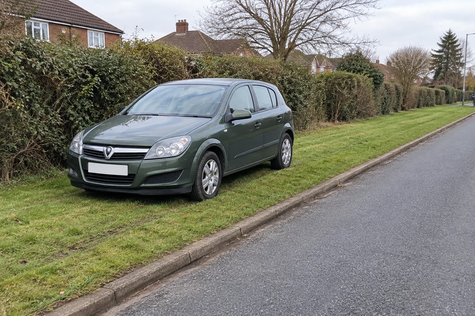 Car parked on a grass verge beside an unmarked British road.