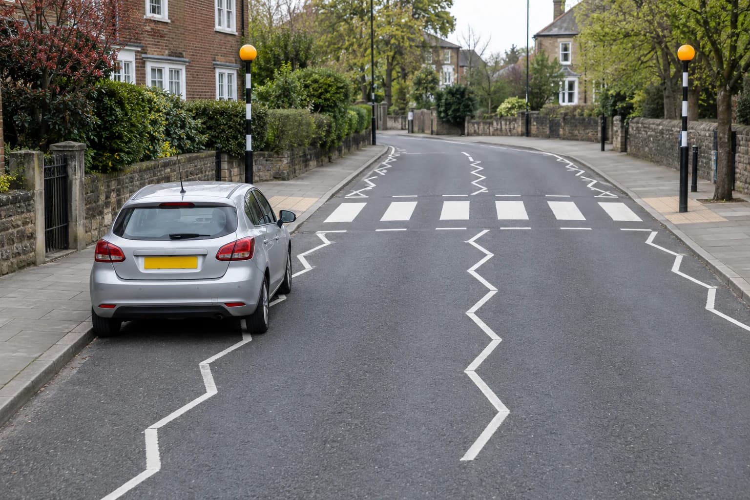Car parked on white approach zigzags at a zebra crossing with Belisha beacons.