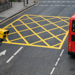 UK yellow box junction from above with traffic enforcement camera on a pole